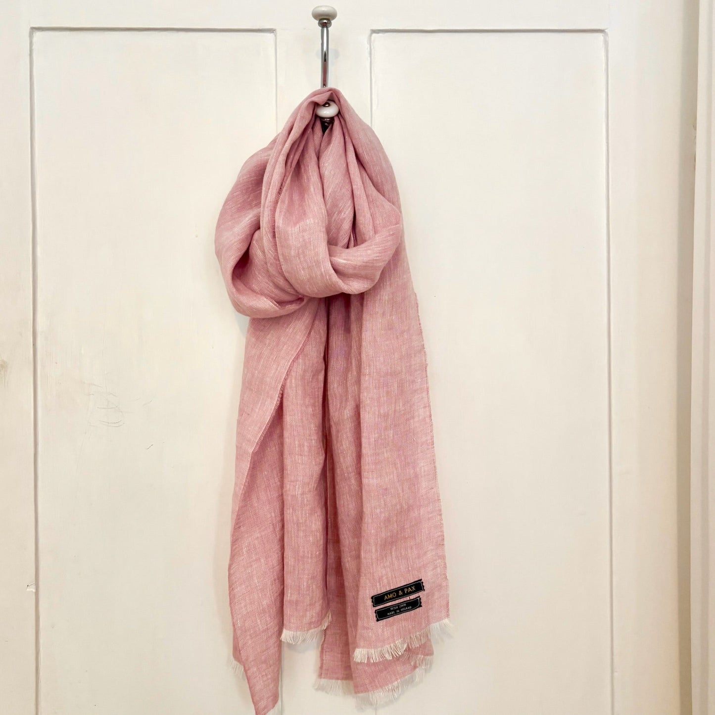 Pink scarf hanging on a white door