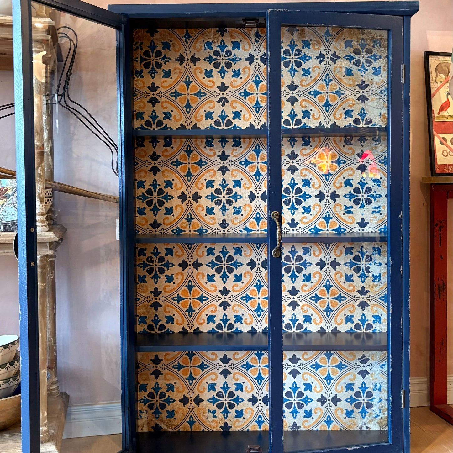 Blue cabinet with patterned doors in a room with decorative elements.