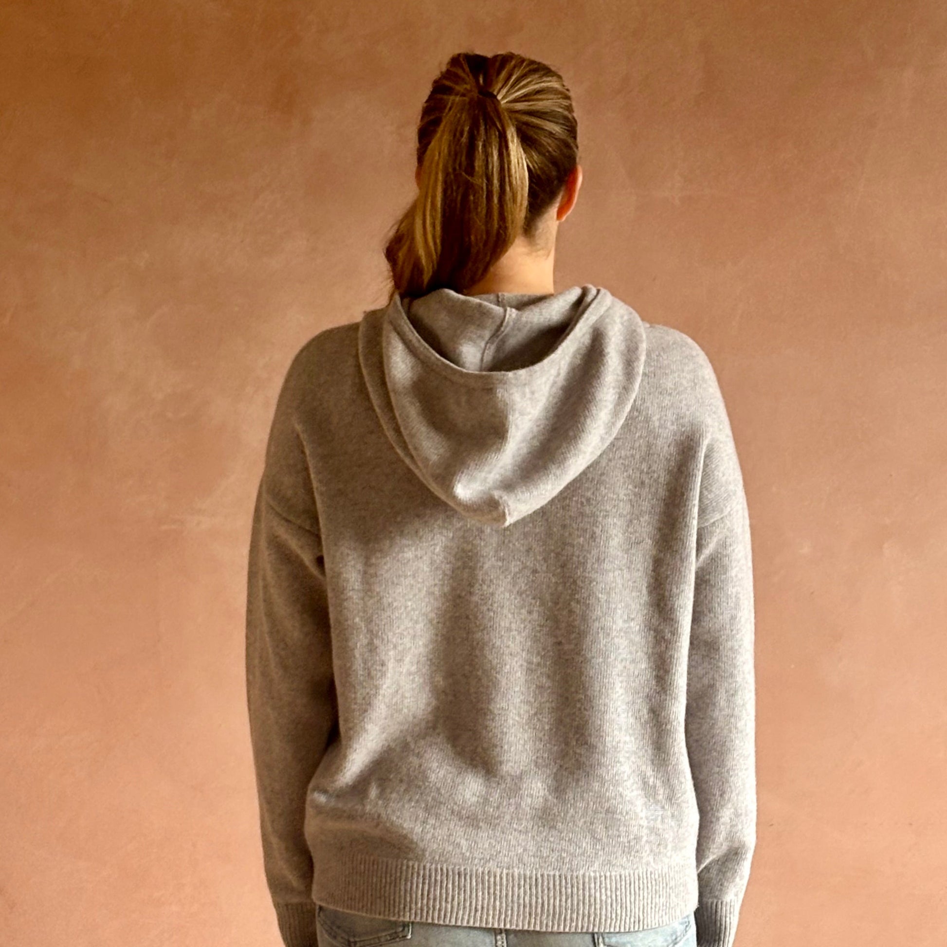 Person wearing a soft gray Irish hoodie against a beige background