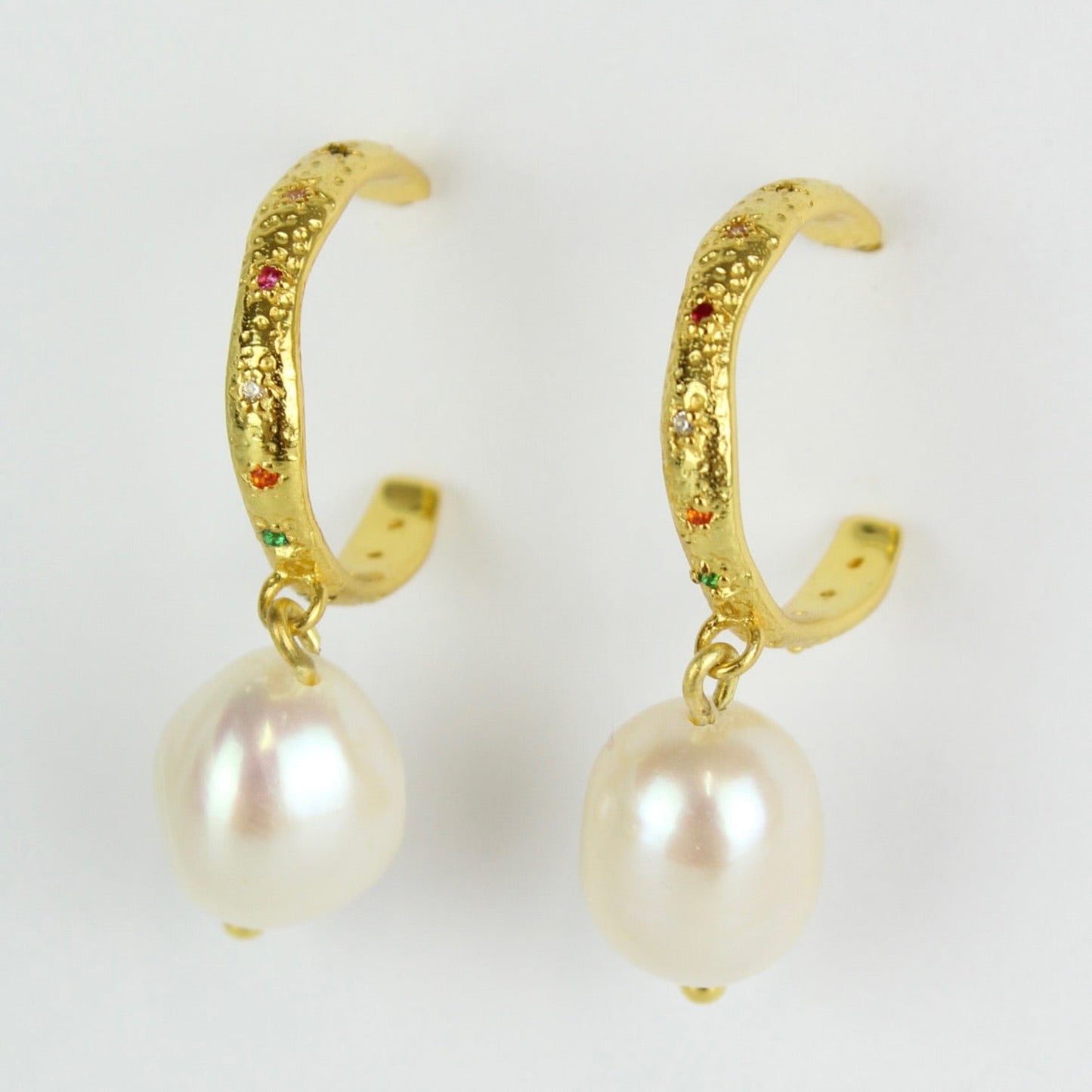 Gold hoop earrings with pearl drops on a white background