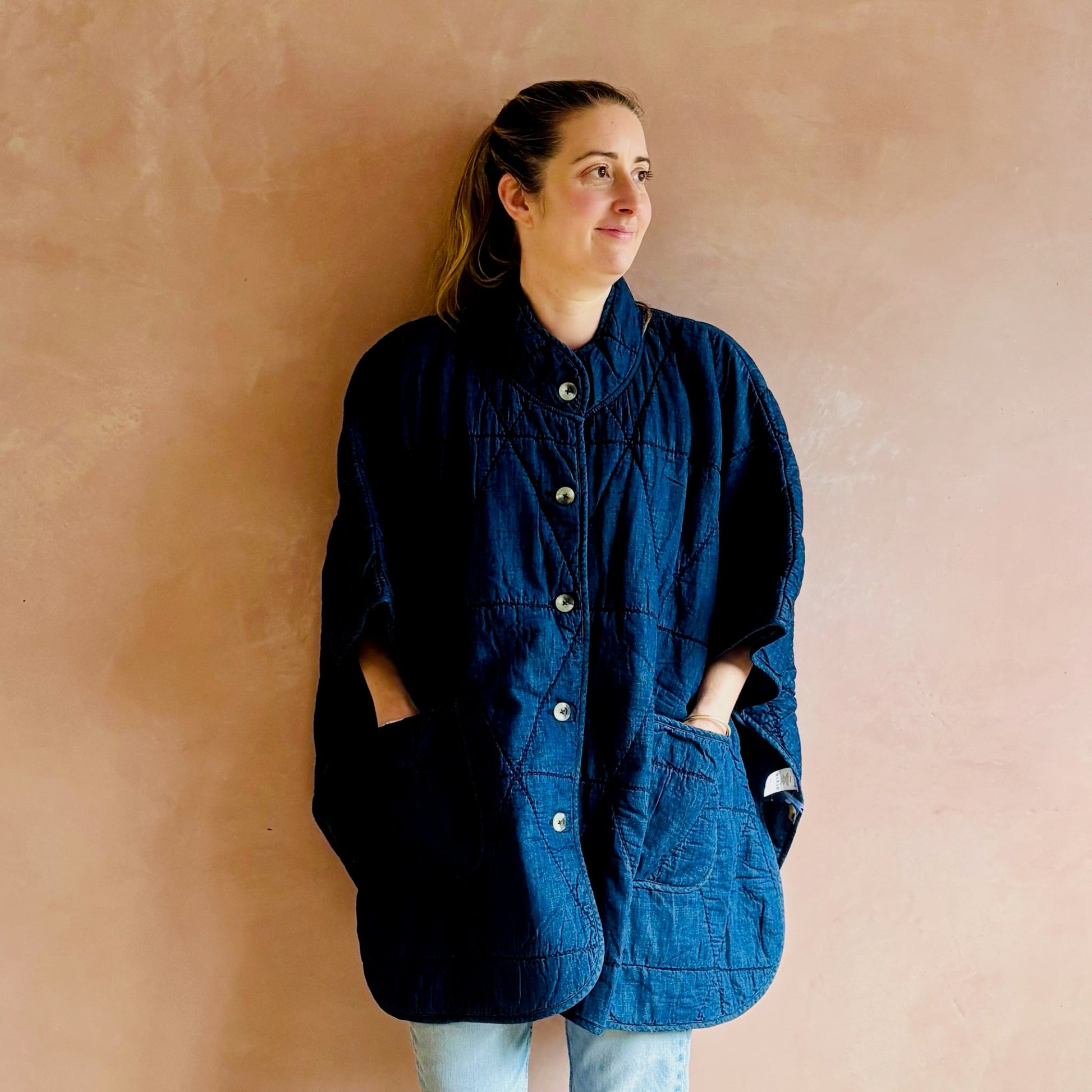 Woman wearing a blue jacket against a beige wall