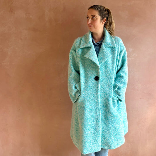 Woman wearing a light blue coat against a pinkish-brown wall