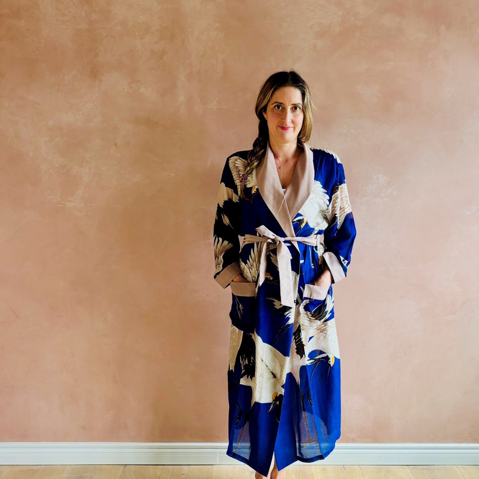 Woman wearing a blue and white patterned robe against a pink wall