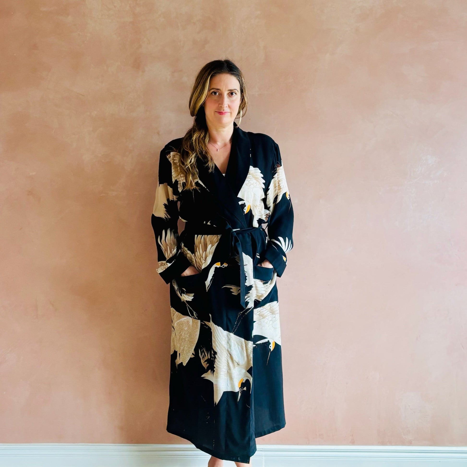 Woman wearing a black patterned robe against a pink wall