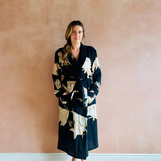 Woman wearing a black patterned robe against a pink wall