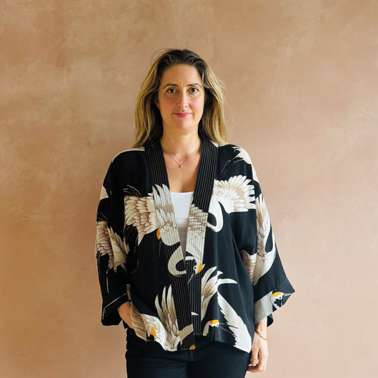 Woman wearing a black kimono with white floral patterns against a beige background