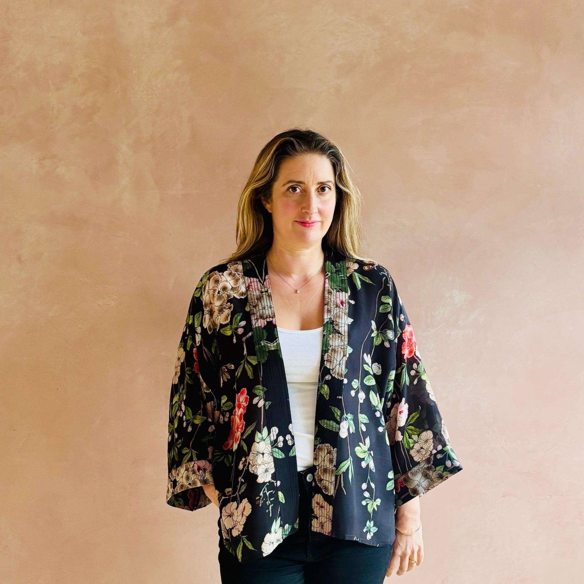 Woman wearing a floral kimono-style jacket against a beige wall
