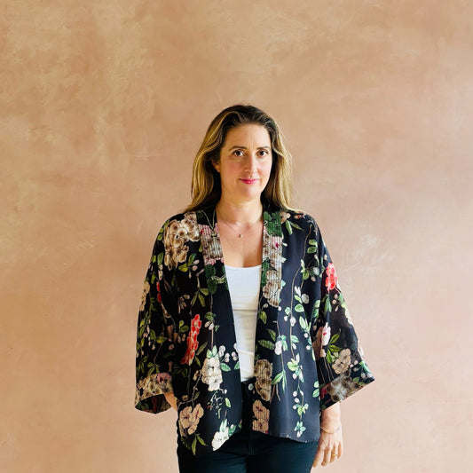 Woman wearing a floral kimono-style jacket against a beige wall