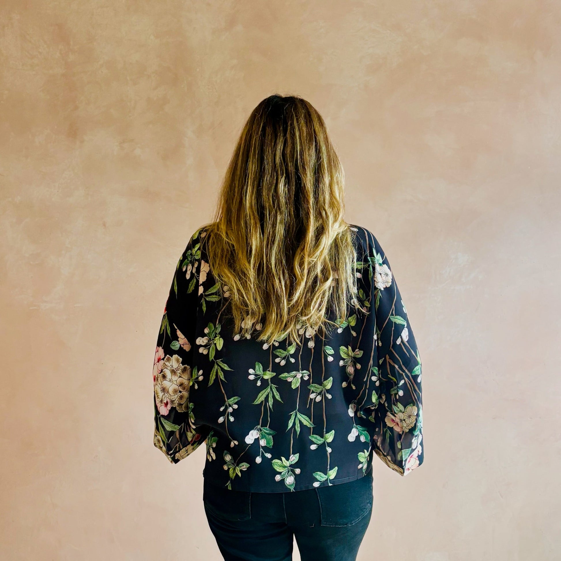 Person wearing a floral kimono against a beige wall