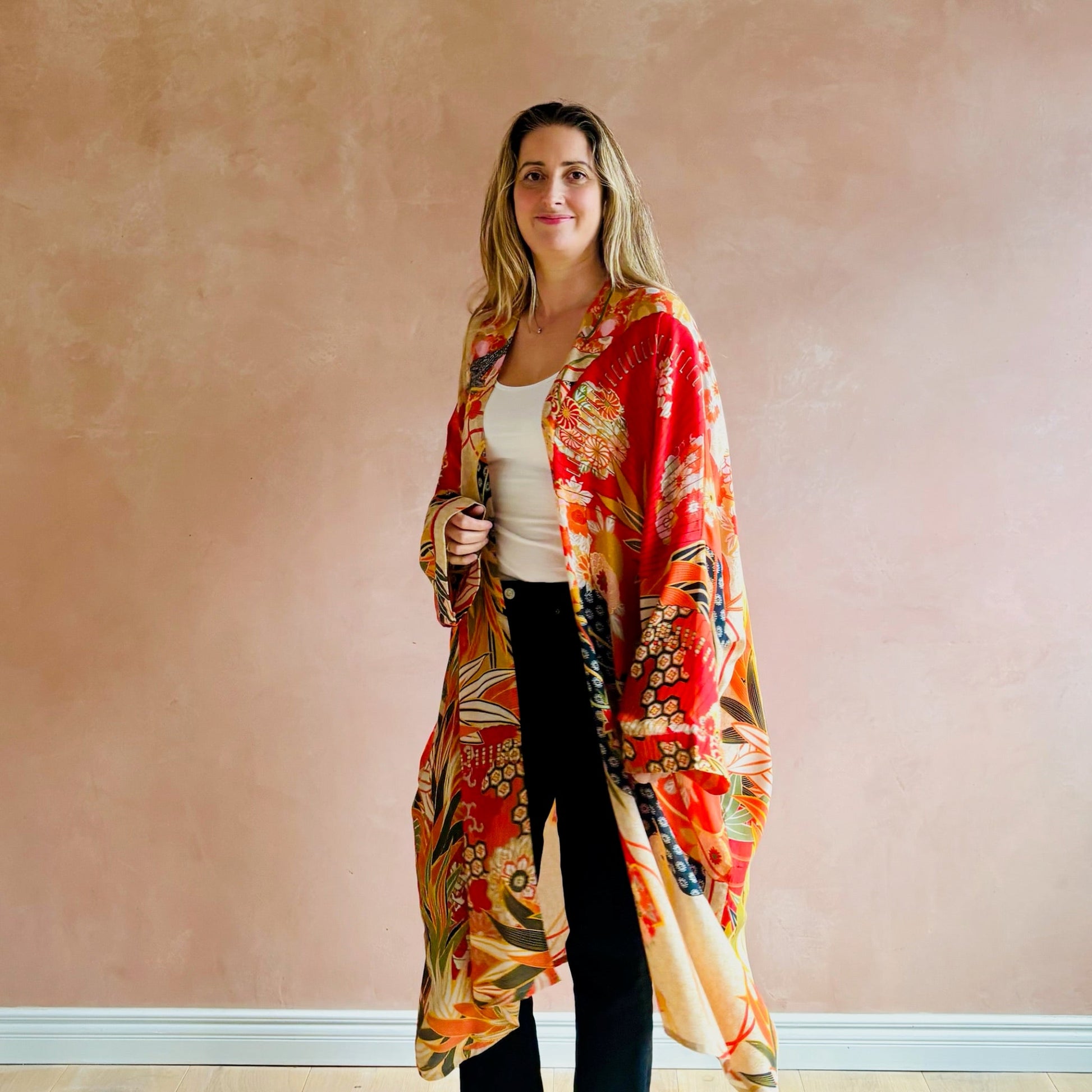 Woman wearing a colorful kimono-style garment against a plain wall.