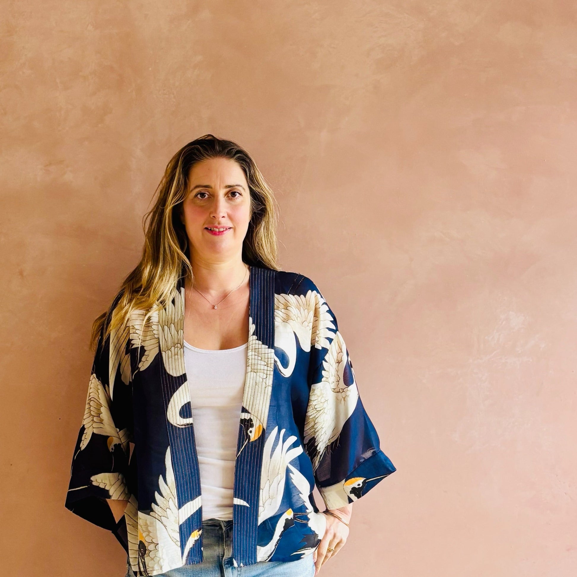 Woman wearing a navy blue kimono with white floral patterns against a beige wall.