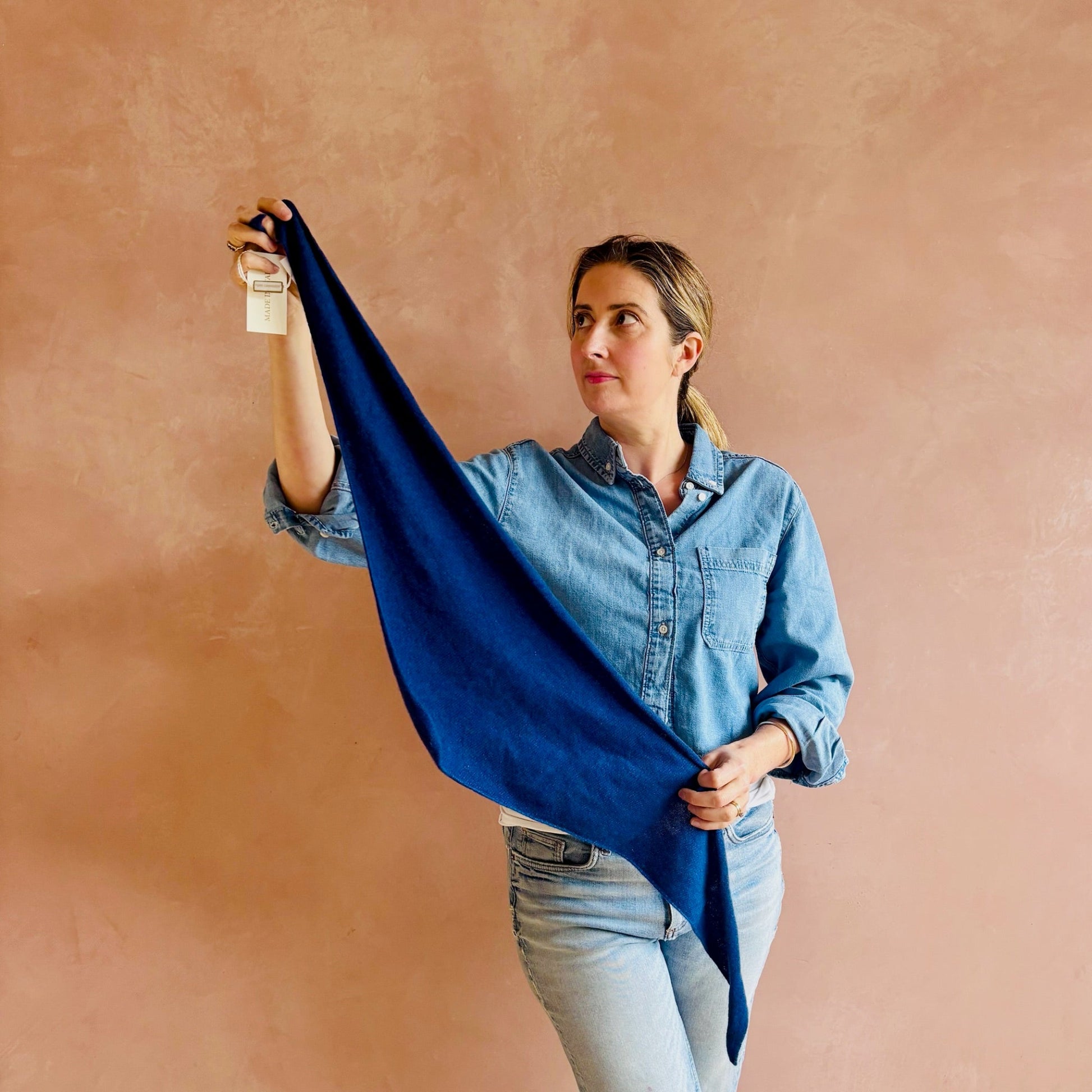 Woman holding a blue scarf against a beige background