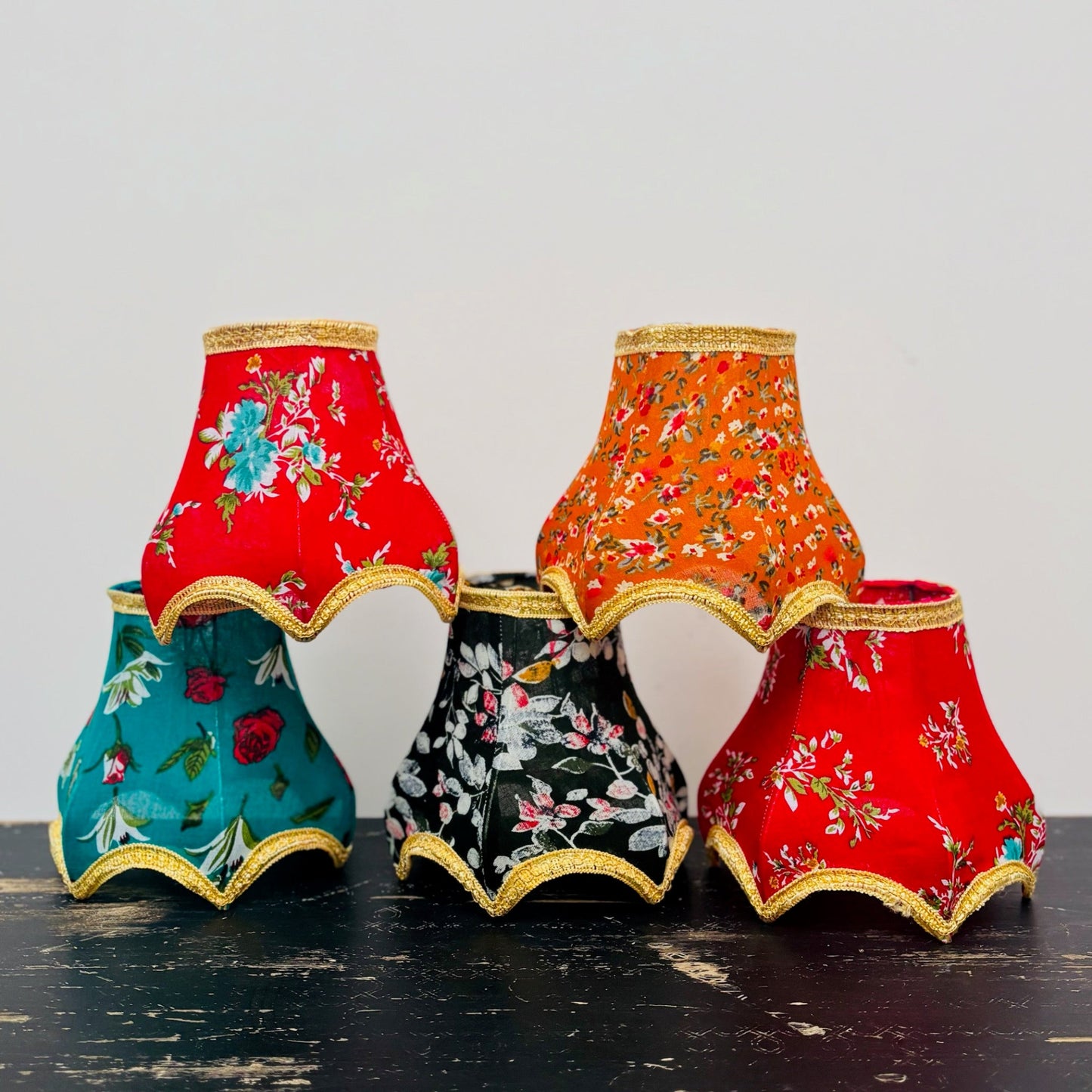 Set of colorful fabric lampshades with floral patterns on a dark surface.