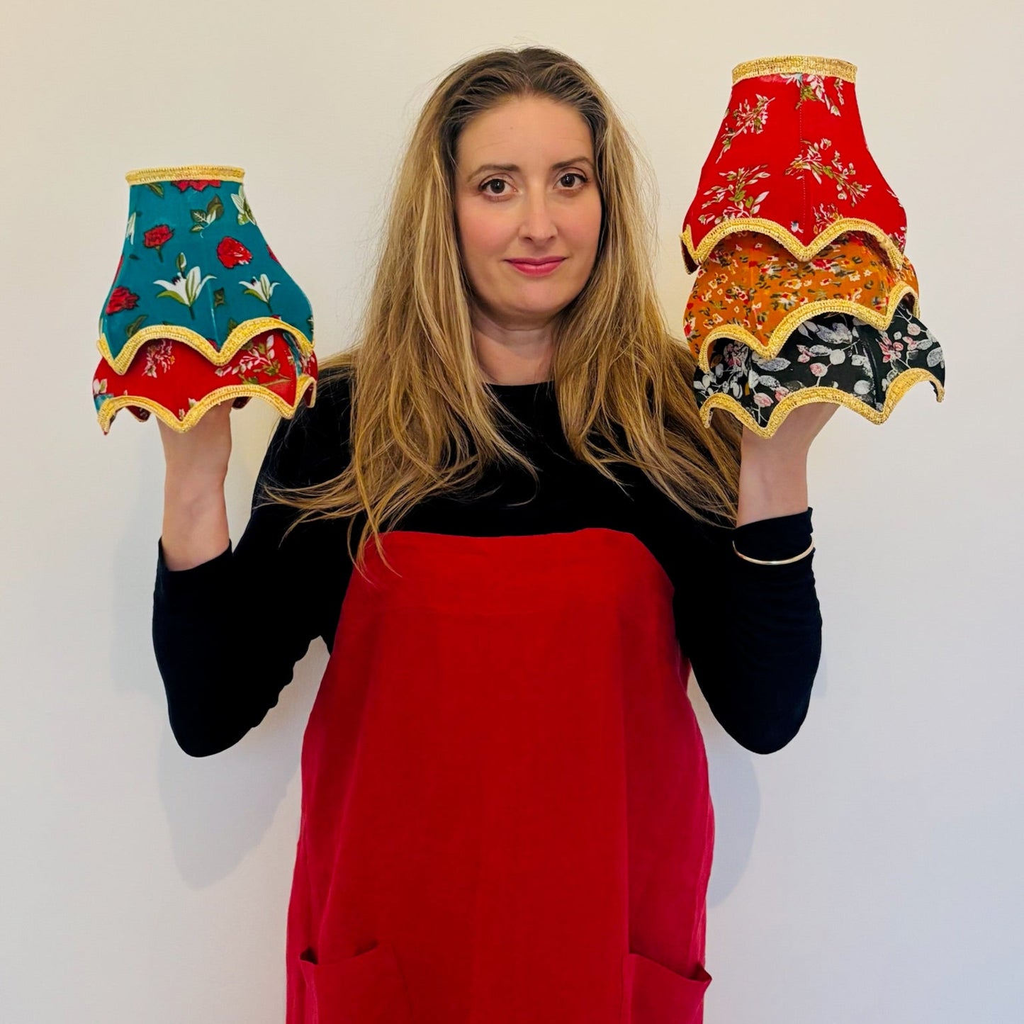 Woman holding two colorful lampshades against a white background