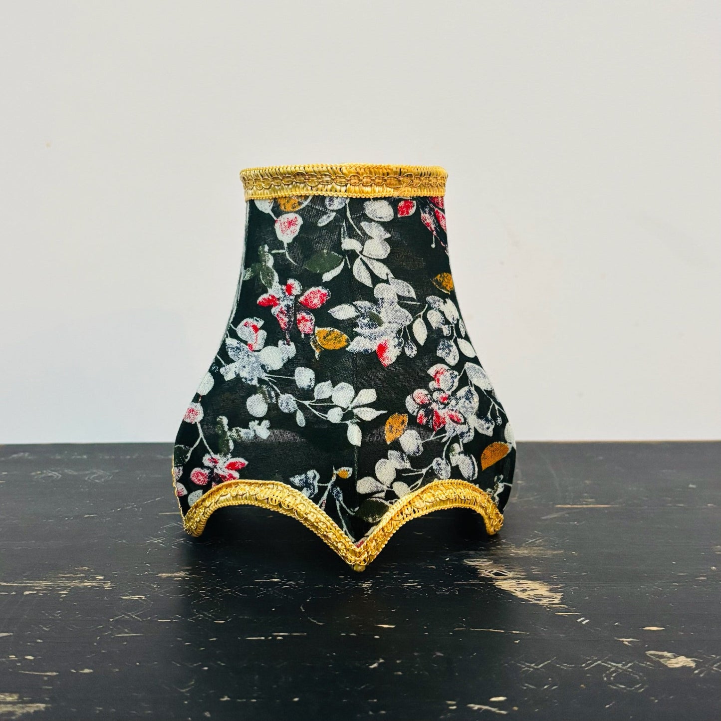 Decorative vase with floral pattern and gold trim on a black surface