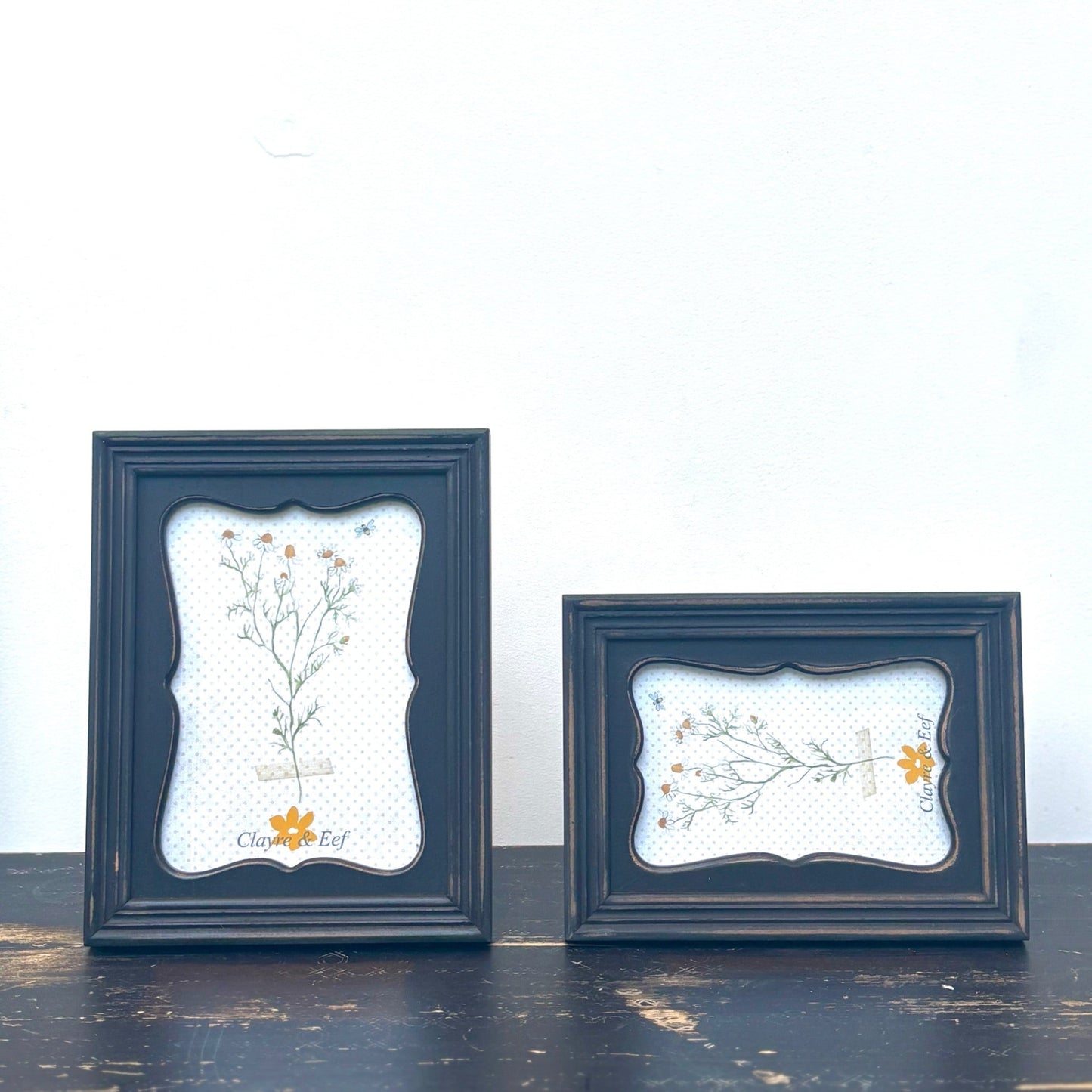 Two dark blue framed artworks with floral designs on a white background