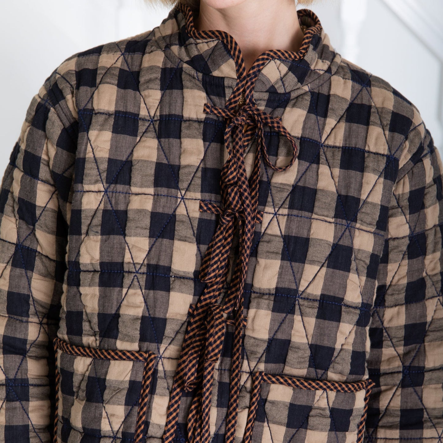Quilted checkered coat with a tie detail on a white background