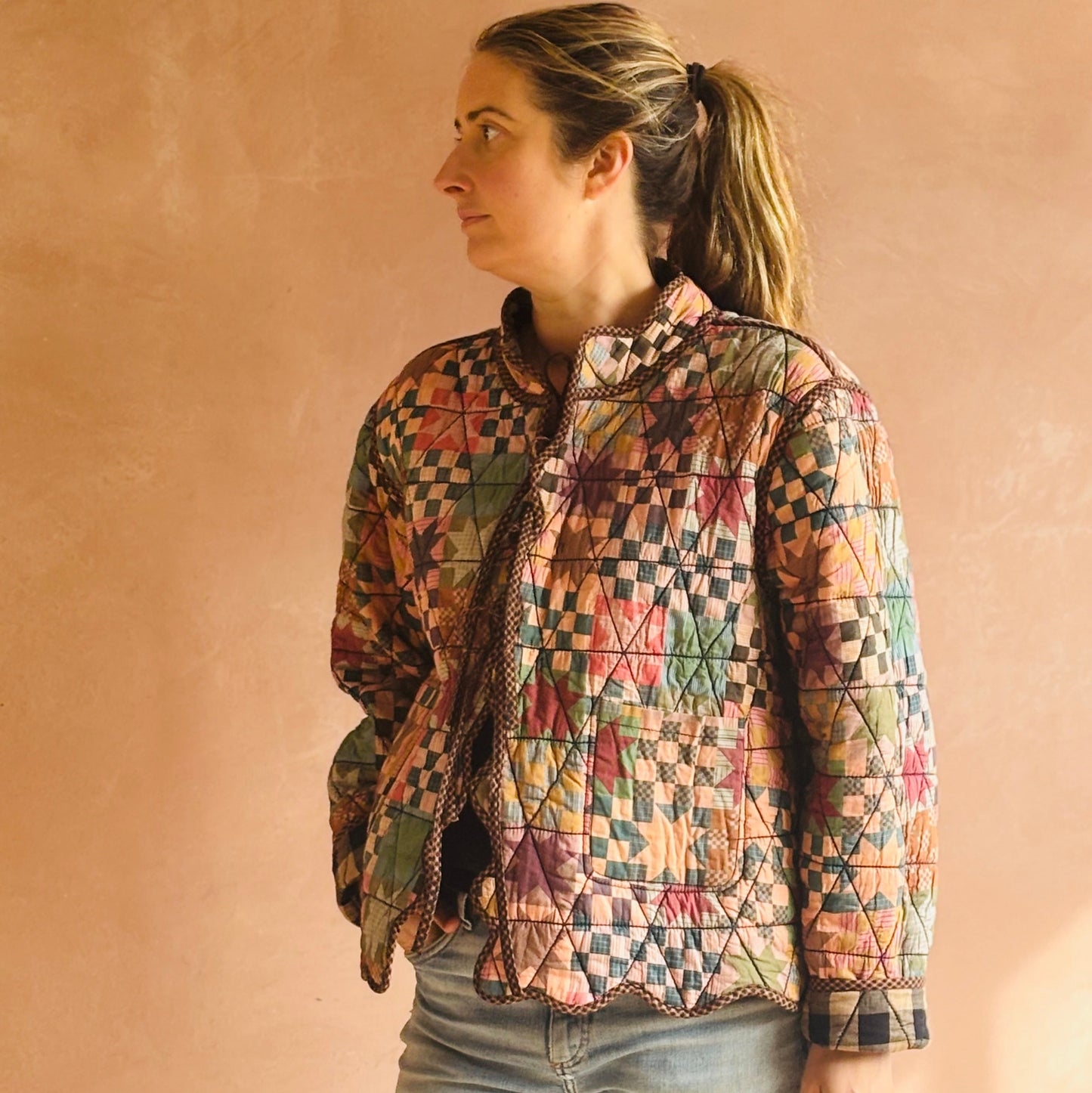 Woman wearing a colorful quilted jacket against a beige background