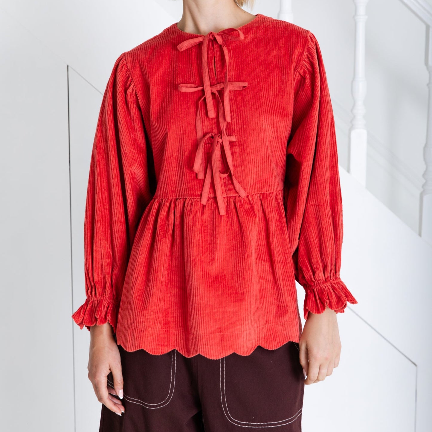 Woman wearing a red blouse with long sleeves and a white background