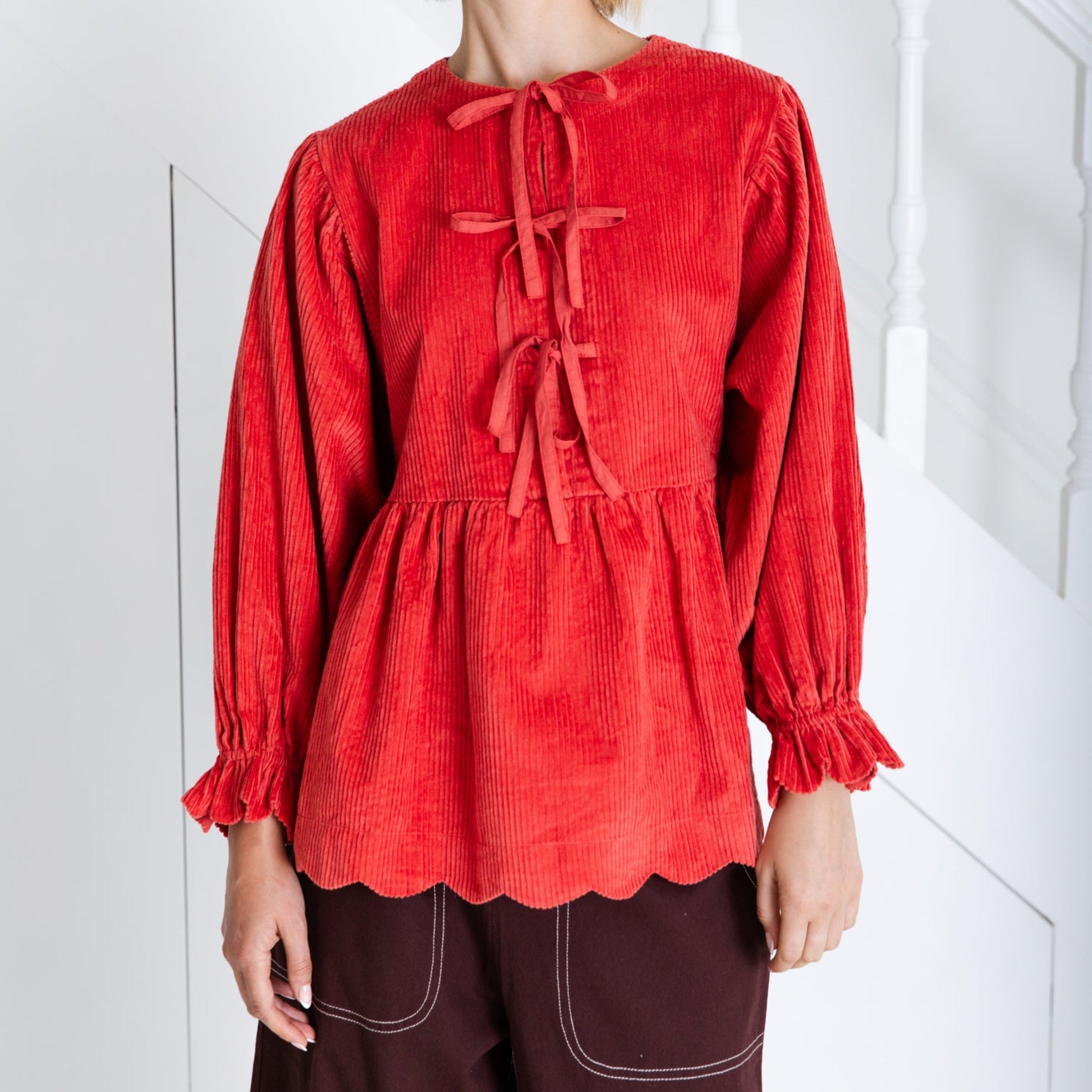 Woman wearing a red blouse with long sleeves and a white background