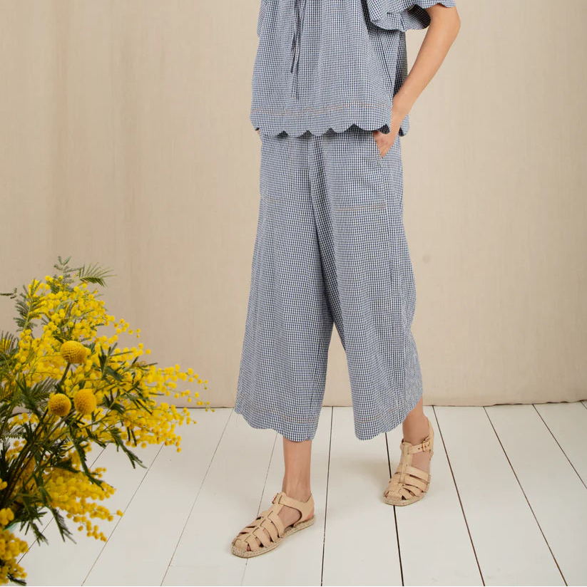 Woman wearing a blue checkered outfit with a plain background