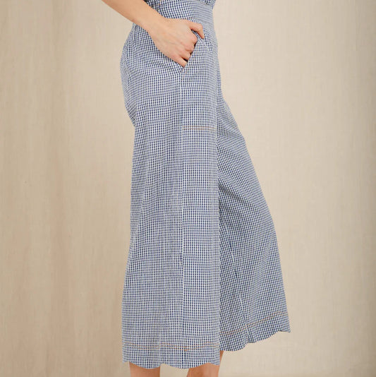 Person wearing a blue checkered dress with wide-leg pants on a beige background