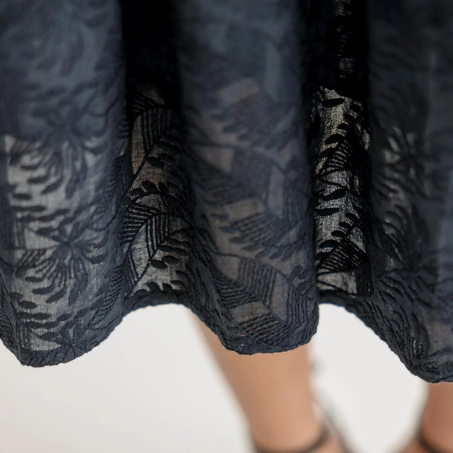 Close-up of a dark blue lace skirt with a blurred background