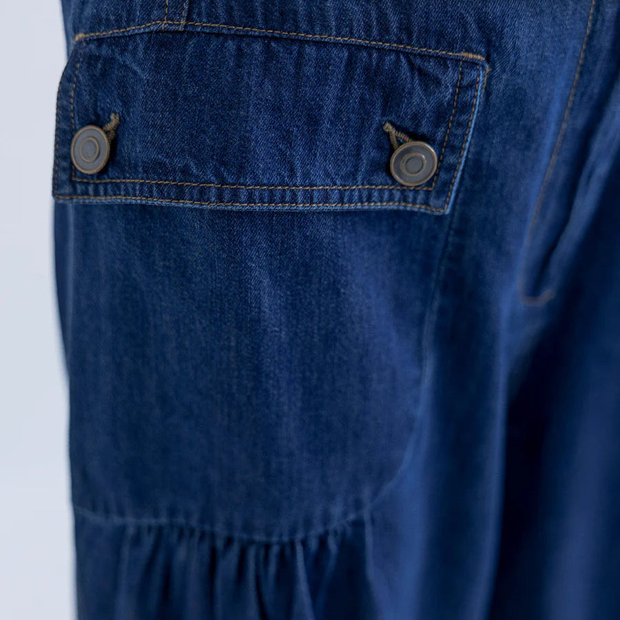 Close-up of blue denim pants with button details on a white background