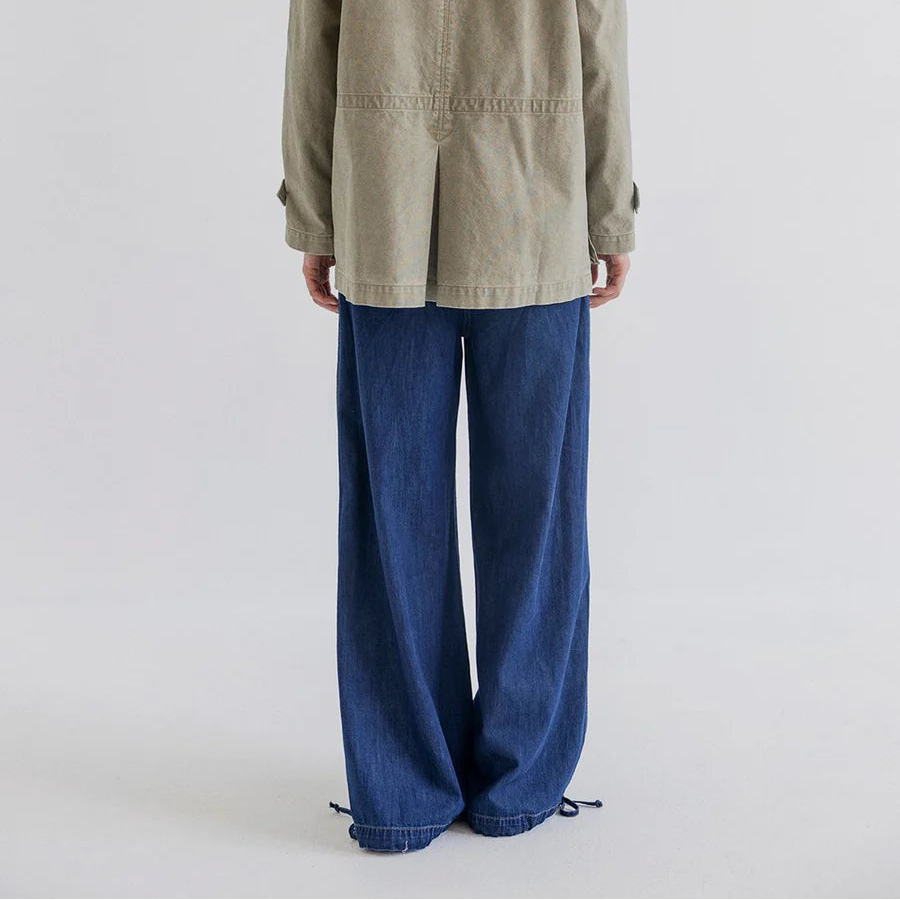 Person wearing a green jacket and blue pants on a white background
