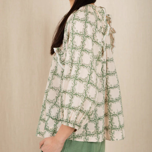 Woman wearing a floral blouse with long sleeves against a beige background