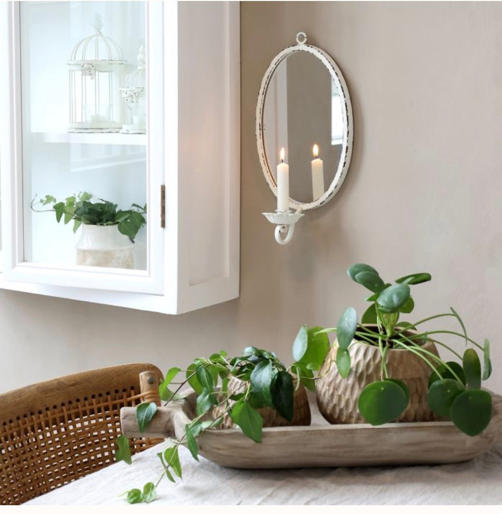 Decorative setting with plants, a mirror, and candles in a home interior.