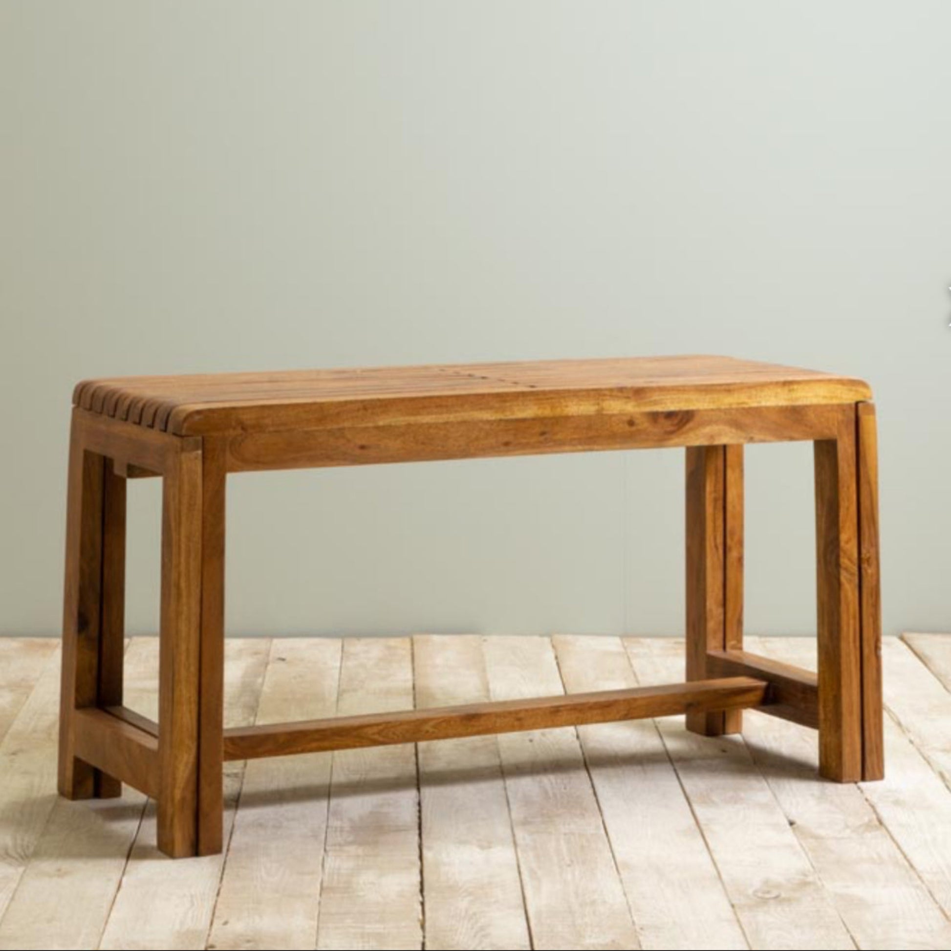 Wooden bench on a wooden floor with a plain wall background