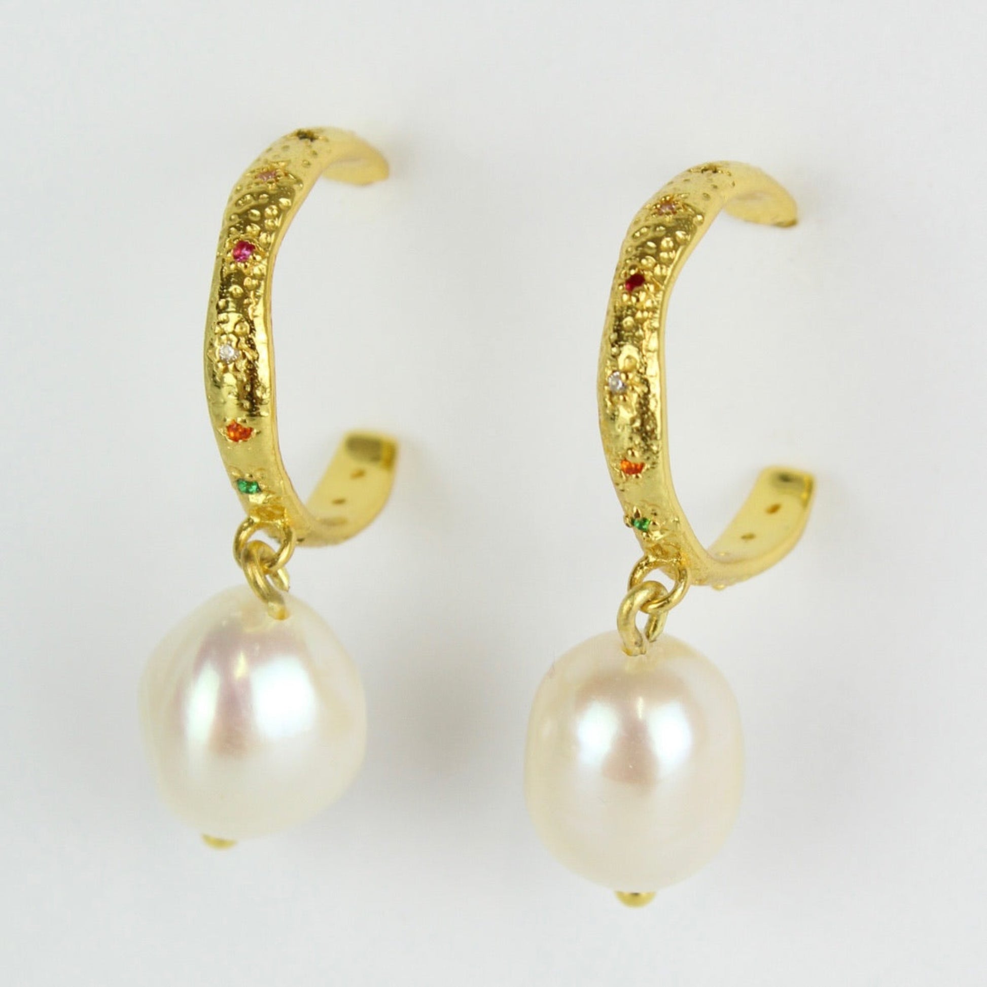Gold hoop earrings with pearl drops on a white background