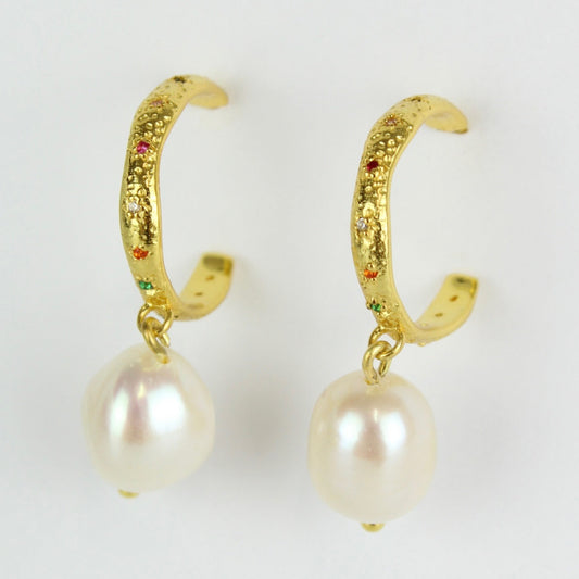 Gold hoop earrings with pearl drops on a white background