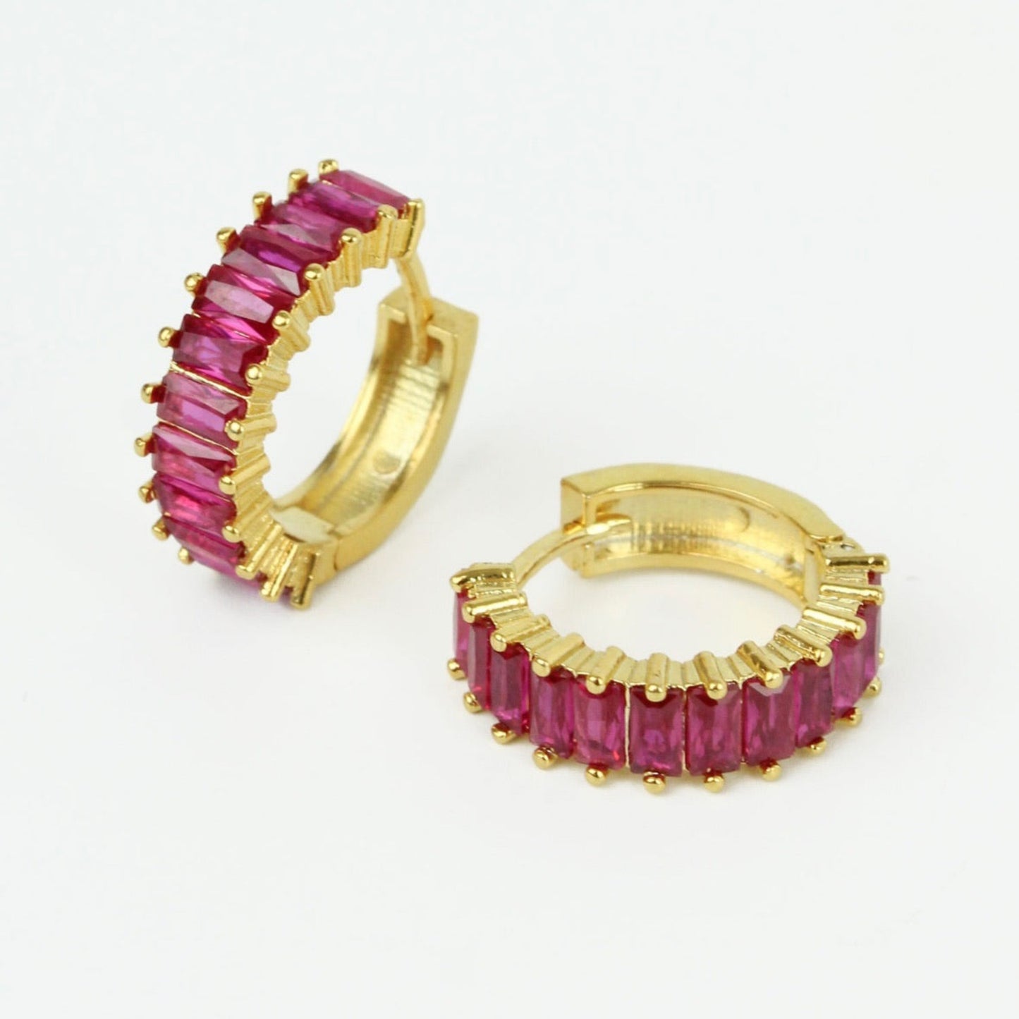 Gold hoop earrings with pink gemstones on a white background