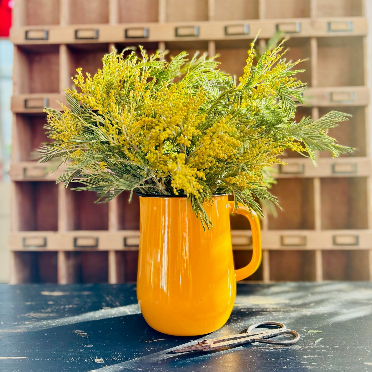 Yellow mug with a bouquet of yellow flowers on a table with a wooden crate background