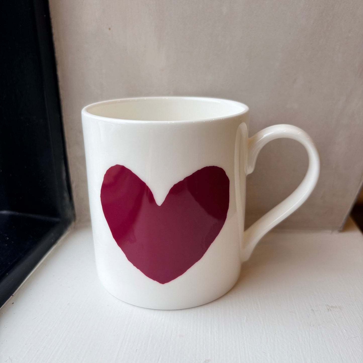 White mug with a red heart on a white surface