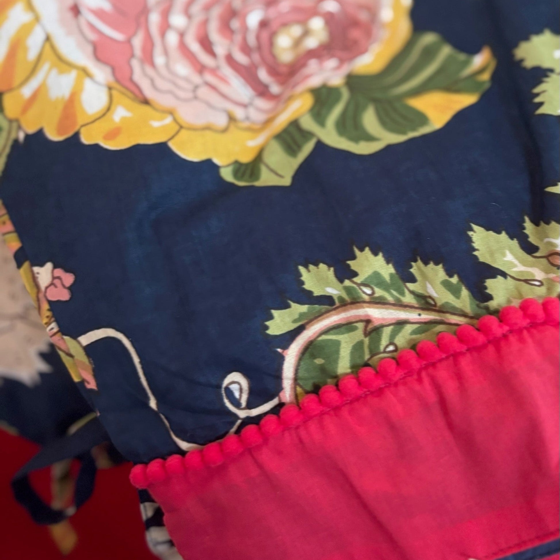 Close-up of a floral fabric with red trim on a blue background