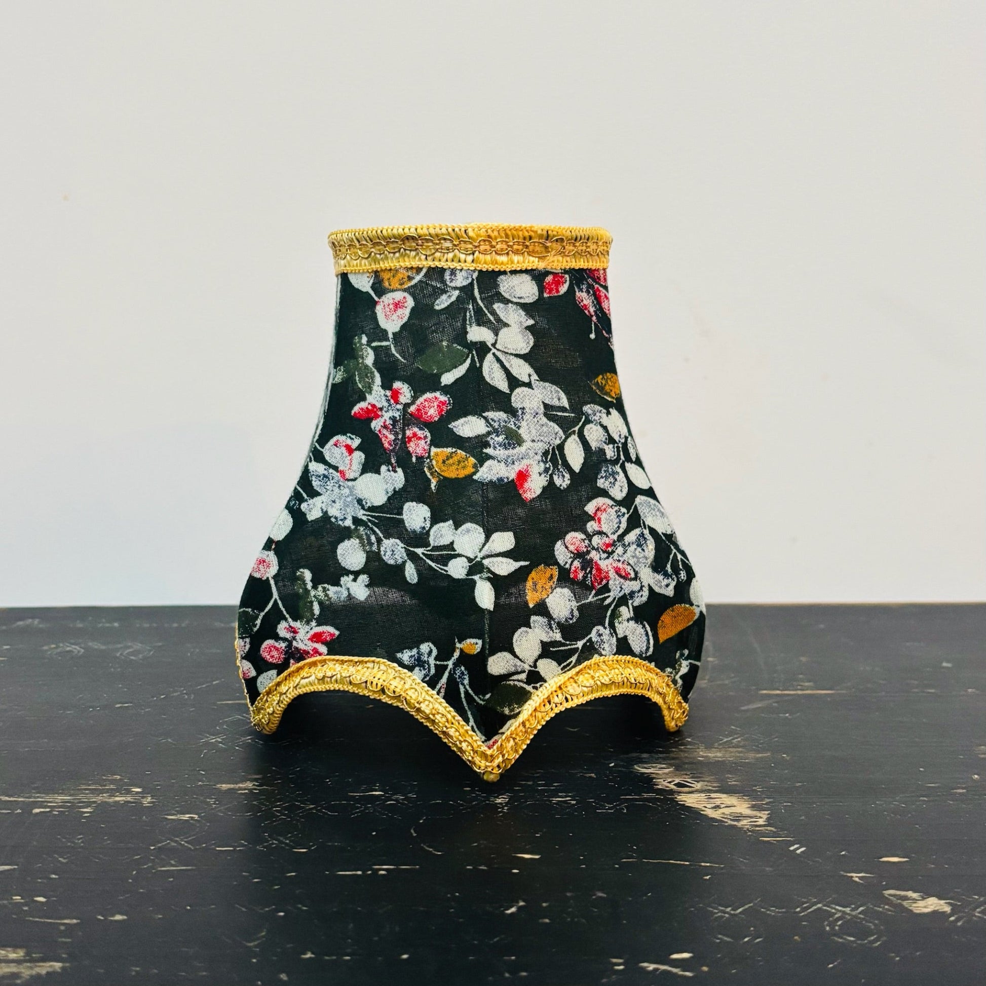 Decorative vase with floral pattern and gold trim on a black surface