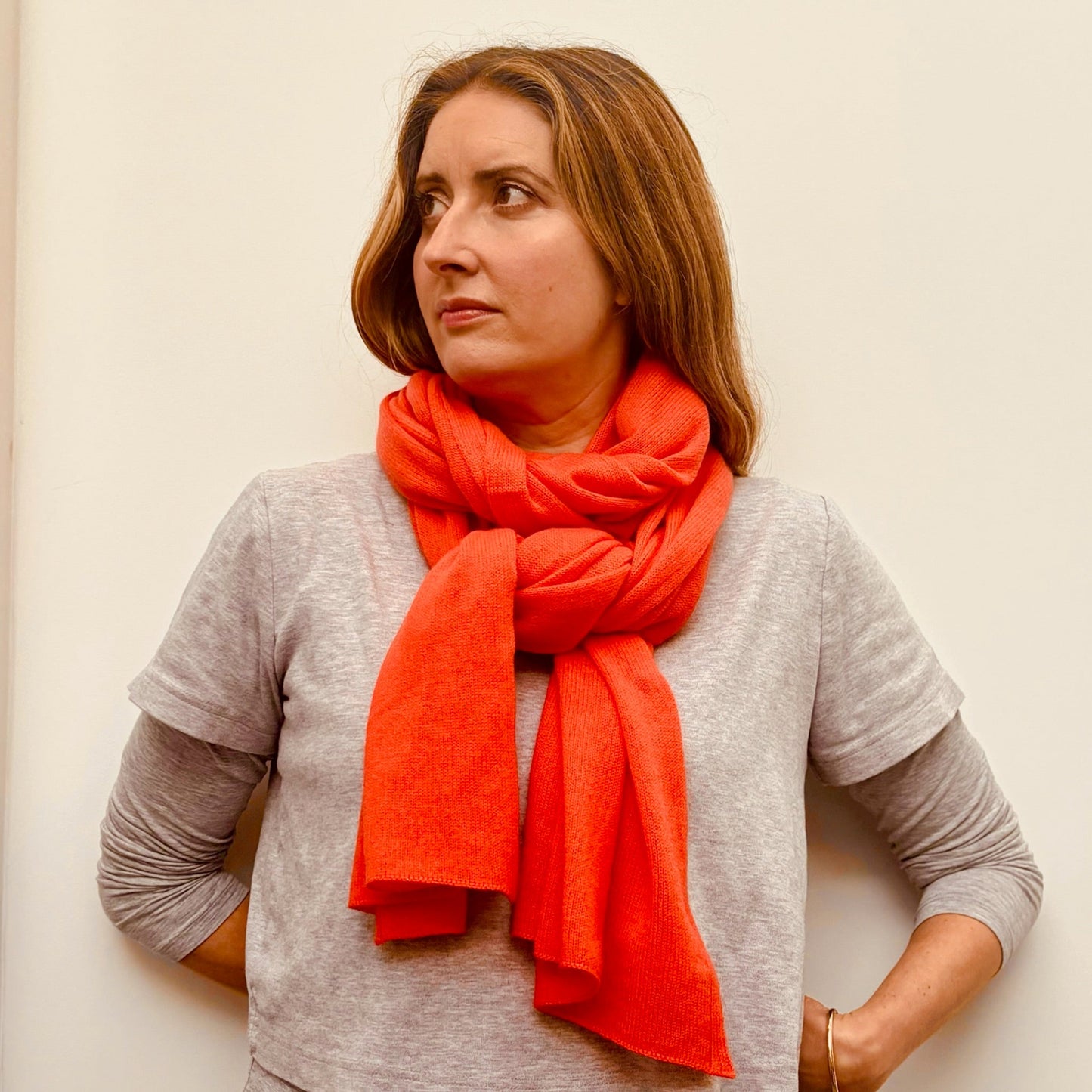 Woman wearing a bright orange scarf against a plain background