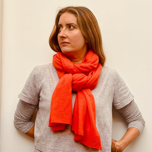 Woman wearing a bright orange scarf against a plain background