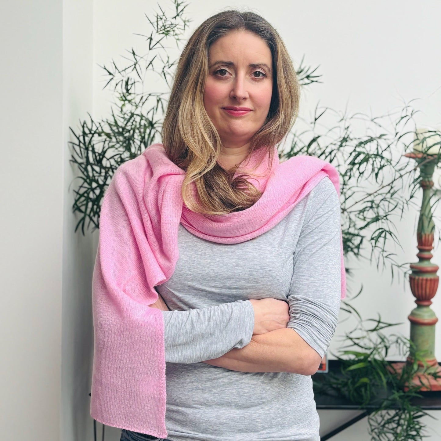 Woman wearing a pink cashmere scarf with plants in the background