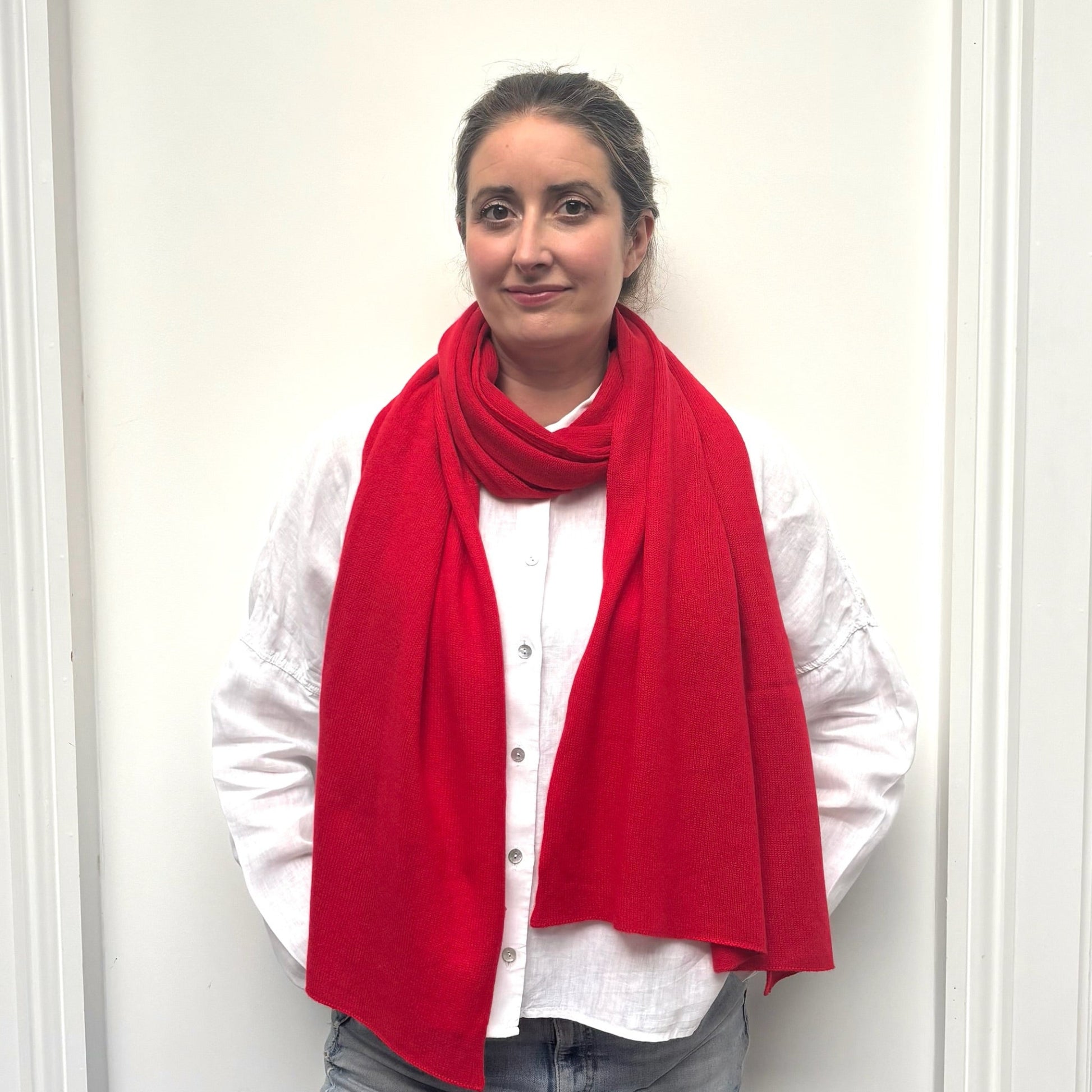 Person wearing a red cashmere scarf and white shirt against a white background