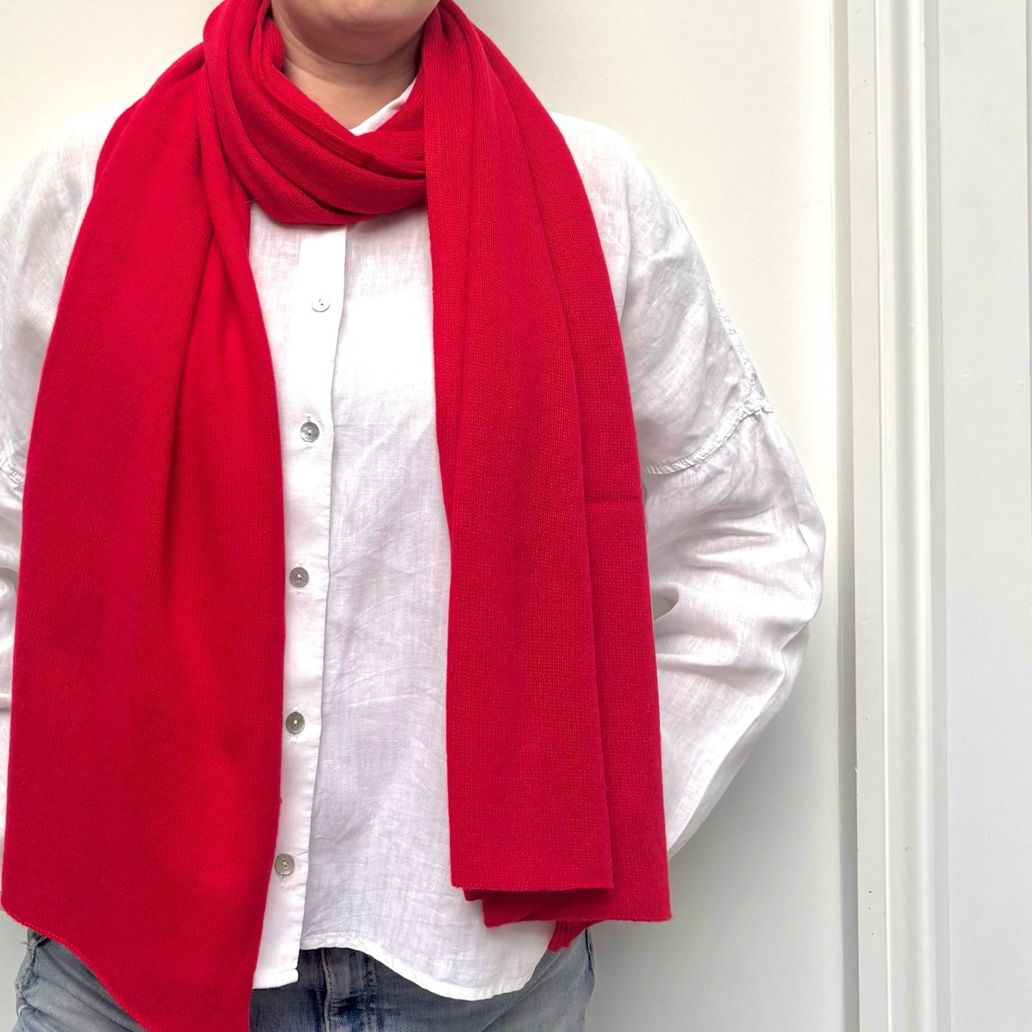Person wearing a red scarf over a white shirt with a neutral background