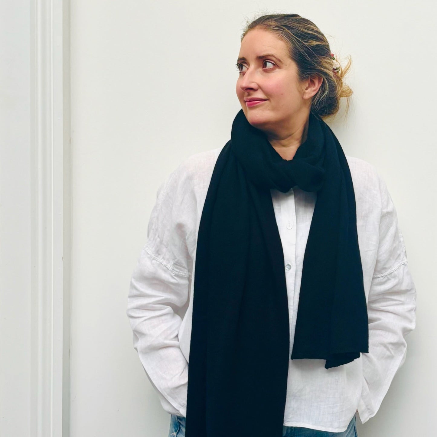 Woman wearing a dark blue scarf and white shirt against a plain background