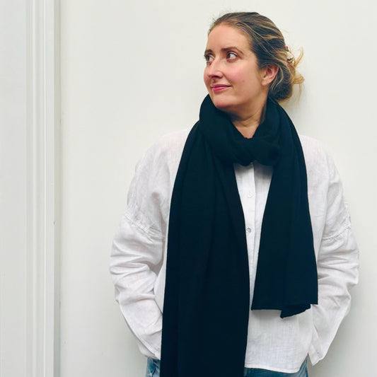 Woman wearing a dark blue scarf and white shirt against a plain background