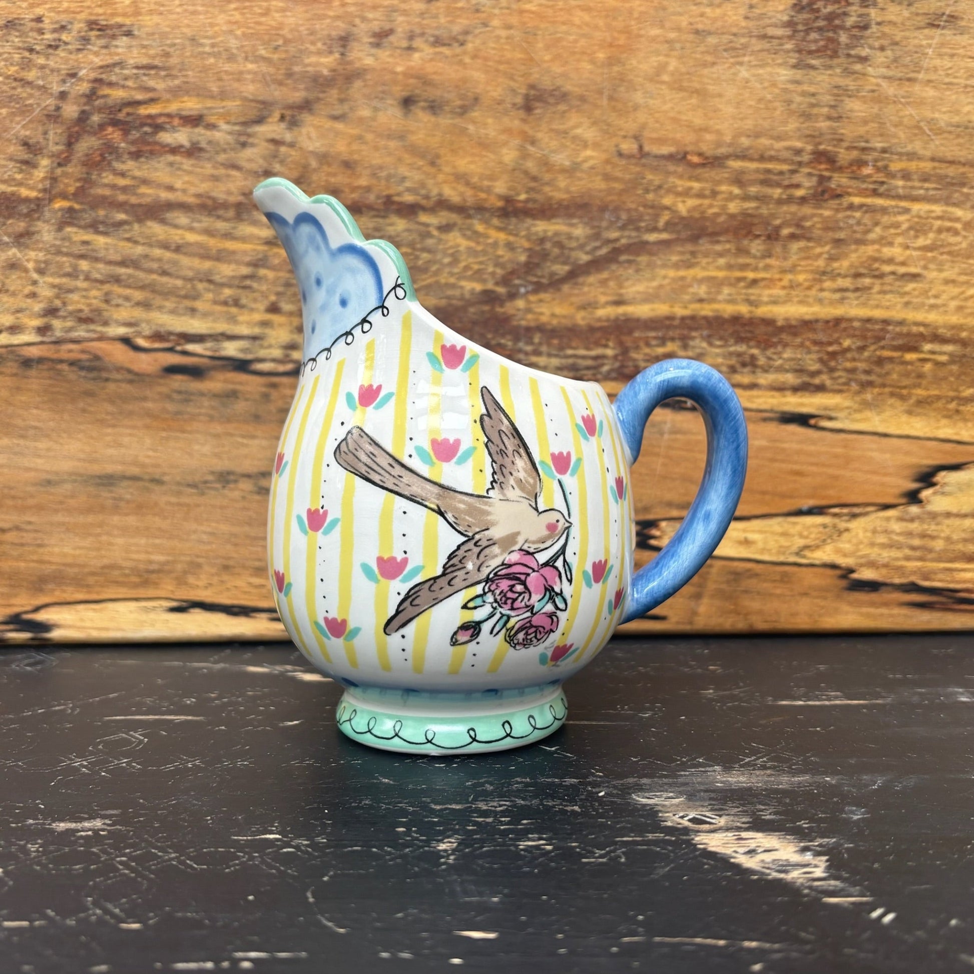 Ceramic jug with bird design on a wooden surface