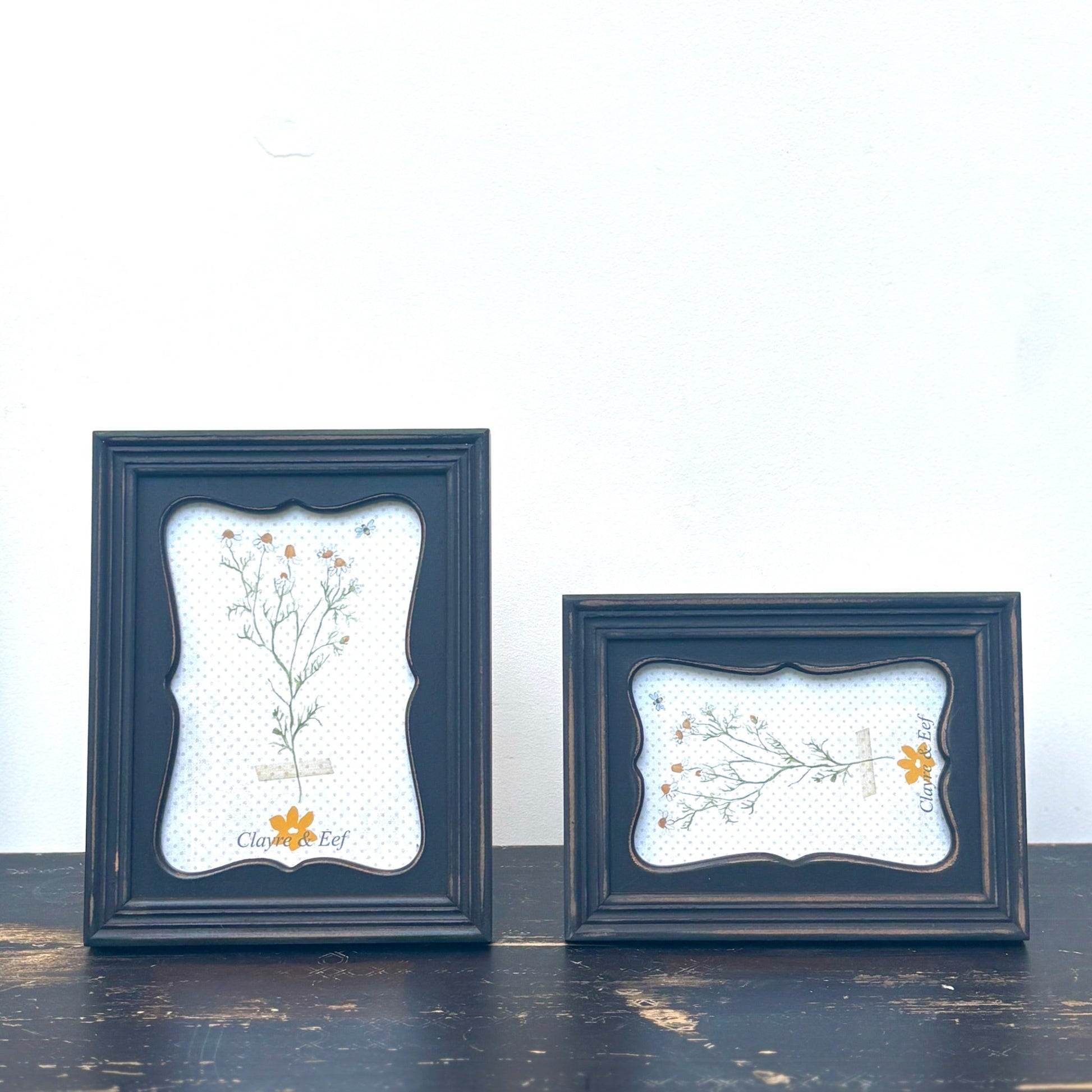Two dark blue framed artworks with floral designs on a white background