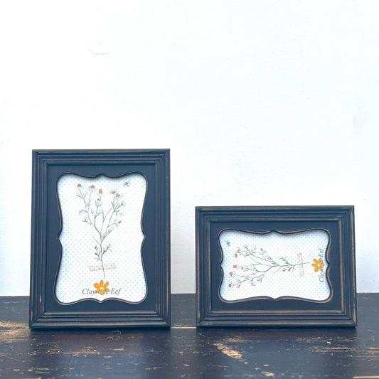 Two dark blue framed artworks with floral designs on a white background