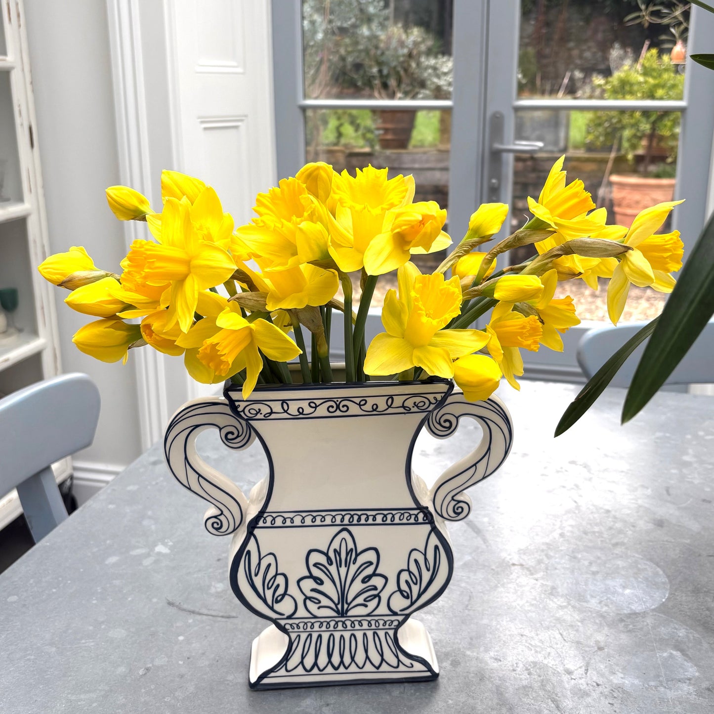 Decorative flat vase with yellow flowers on a table indoors